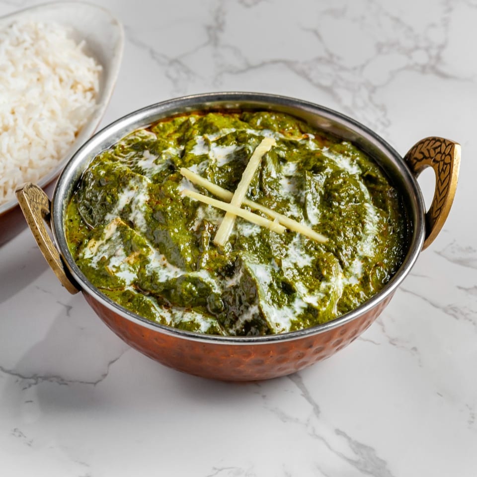 Palak Paneer, a vibrant green spinach and cheese curry, in a copper bowl with a side of white rice.