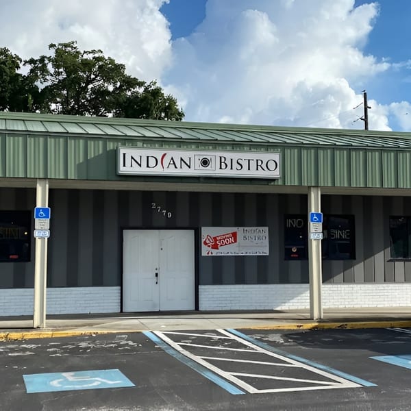 Exterior of Indian Bistro restaurant with a "Opening Soon" sign and handicapped parking spaces.