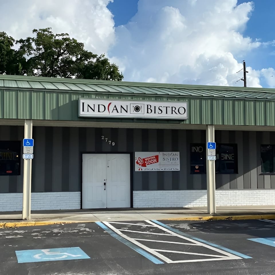 Exterior of Indian Bistro restaurant with a "Opening Soon" sign and handicapped parking spaces.