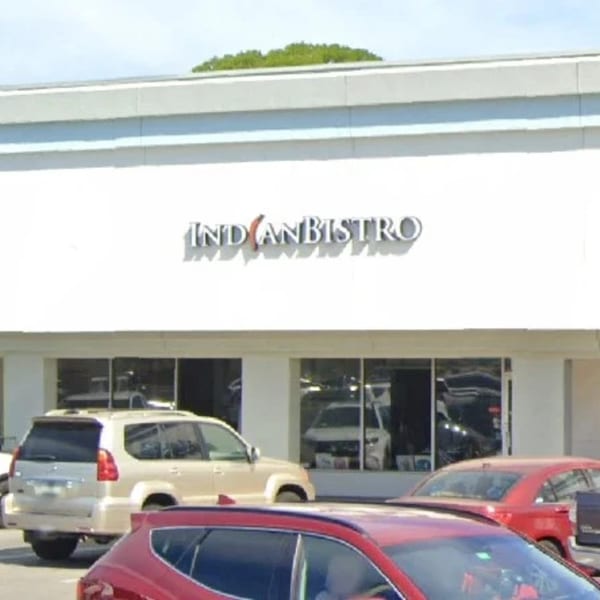 Exterior view of the Indian Bistro restaurant with cars parked in front.